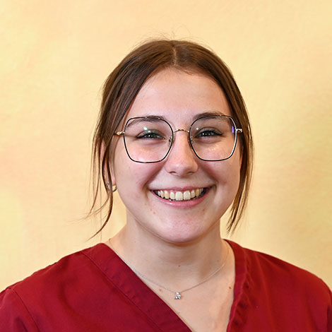 Porträtfoto einer Mitarbeiterin mit langen, nach hinten gebundenen Haaren und Brille